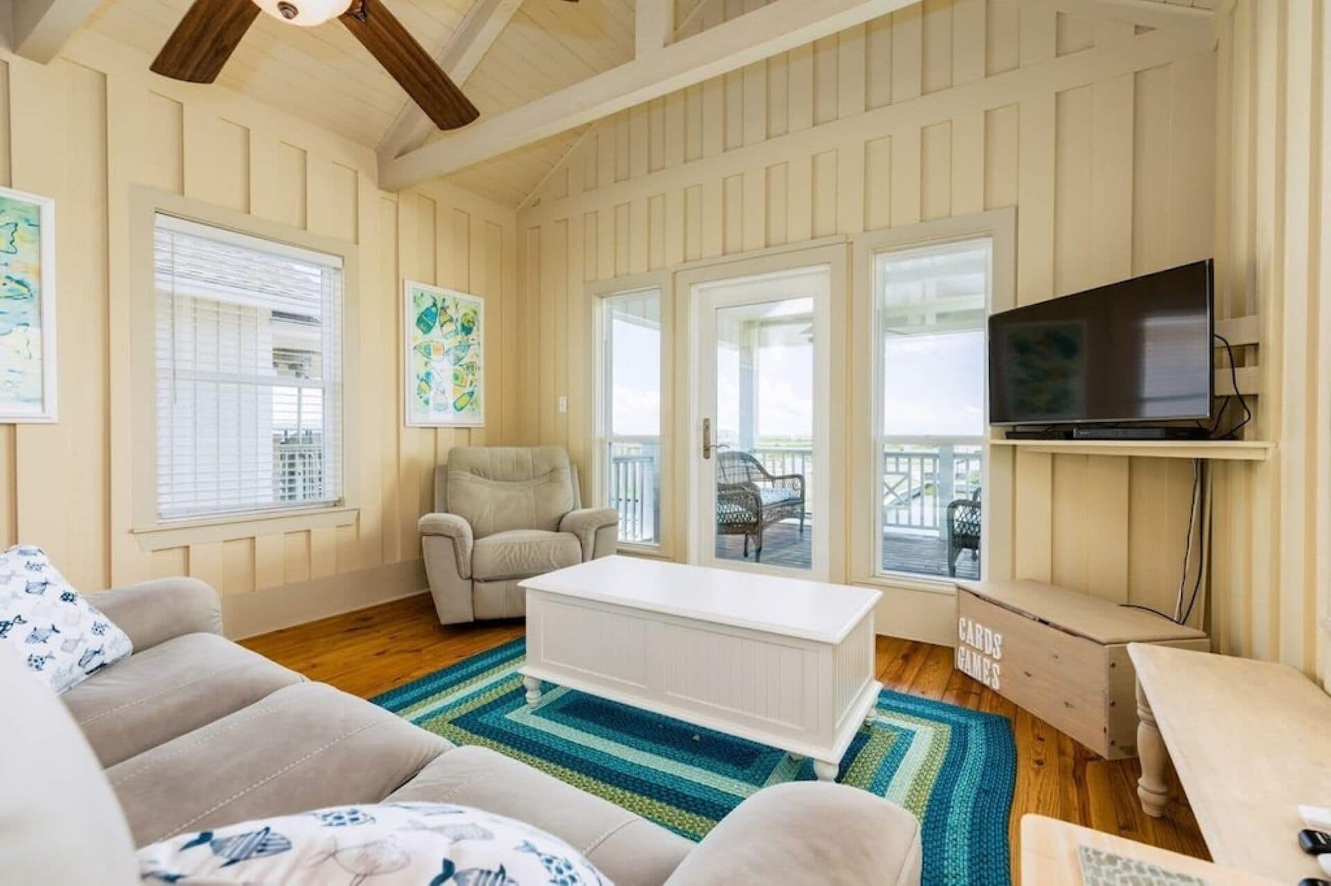 A cozy living room with a white sofa, a beige armchair, a white coffee table, and a TV on a wooden stand.
