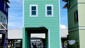 A two-story building with a green exterior and white trim. - Laguna Harbor Cottage (Bolivar Peninsula)