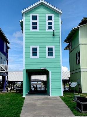 A two-story building with a green exterior and white trim. - Laguna Harbor Cottage (Bolivar Peninsula)