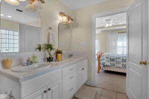 A bathroom with dual sinks, a large mirror, and a ceiling fan. - Happy Ours (Panama City Beach)