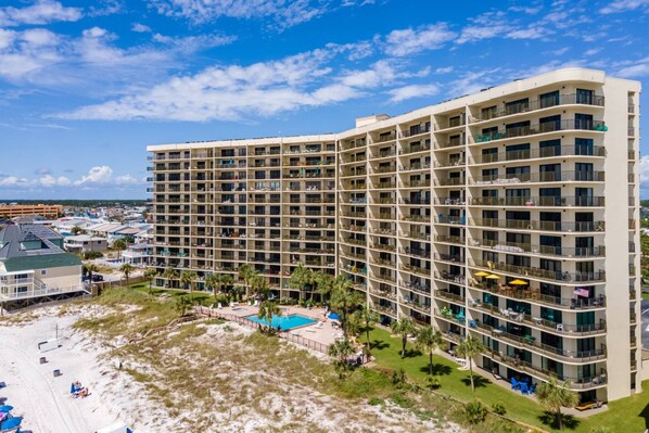 A high-rise hotel with multiple balconies, a pool, and a beach area. - Commodore by iTrip Panama City Beach (Panama City Beach)