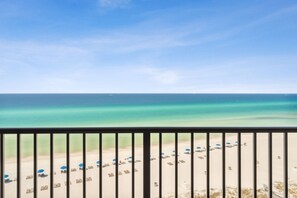 A beach view with a clear sky, a calm sea, and a row of beach umbrellas and lounge chairs. - Commodore by iTrip Panama City Beach (Panama City Beach)