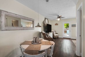 A dining area with a round table, chairs, and a large mirror on the wall. - Good Times and Tan Lines (Panama City Beach)