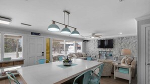 A modern kitchen with a central island, teal chairs, and a marble backsplash. - Sandy Shores (Panama City Beach)