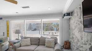 A living room with a sofa, a lamp, a television, and a stone wall. - Sandy Shores (Panama City Beach)