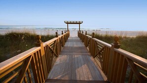 A wooden boardwalk leading to a beach with a wooden pergola at the end. - Sandy Shores (Panama City Beach)