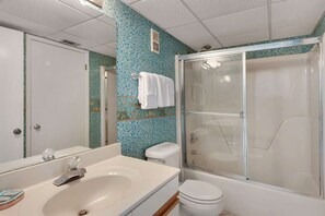 A bathroom with a shower, toilet, and sink.
