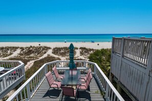 A deck with a table and chairs overlooking a beach. - Emerald Winds (Panama City Beach)