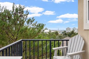 A balcony with a white Adirondack chair, a railing, and a view of houses in the background. - All Decked Out - 140 Southfield (Panama City Beach)