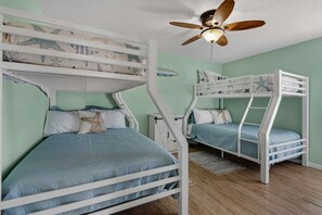 Quarto com beliches, ventoinha no teto e interruptor de luz.