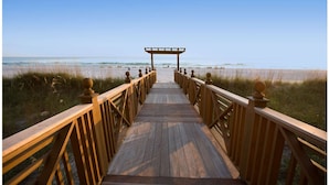 A wooden boardwalk leading to a beach with a wooden pergola at the end. - Sunbird Beach Resort 1211 E (Panama City Beach)