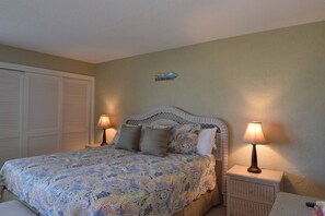 A bedroom with a bed, two bedside tables with lamps, a closet, and a decorative wall piece.
