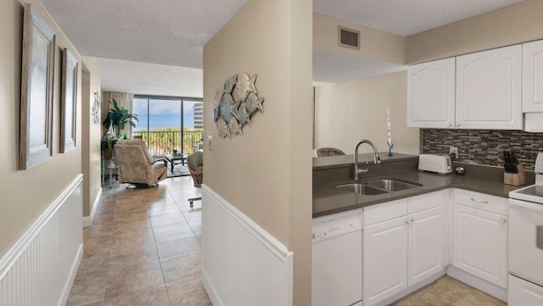 A modern kitchen with white cabinets, a stainless steel sink, and a tiled backsplash.