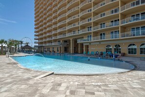 A hotel with a large pool area, multiple balconies, and a Ferris wheel in the background. - Calypso Resort by iTrip Panama City Beach (Panama City Beach)