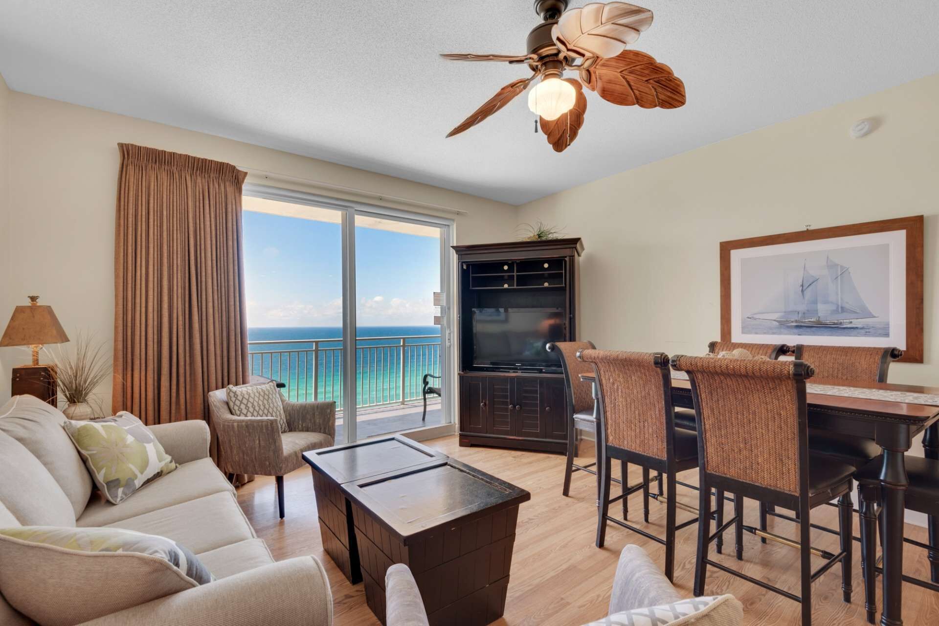 A spacious living area with a balcony, a dining set, and a ceiling fan.
