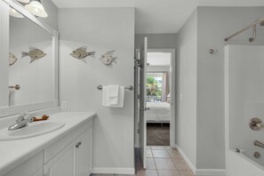 A bathroom with a sink, mirror, and decorative fish wall art.