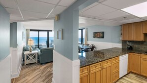 A modern kitchen with wooden cabinets, granite countertops, and a view to the outside. - Watercrest by iTrip Panama City Beach (Panama City Beach)