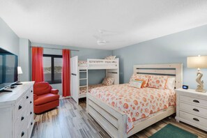 A bedroom with bunk beds, a desk with a chair, a TV, and a lamp. - Watercrest by iTrip Panama City Beach (Panama City Beach)