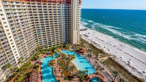 A high-rise hotel with multiple balconies, a pool area, and a beach view. - Shores of Panama by iTrip Panama City Beach (Panama City Beach)