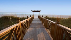 A wooden boardwalk leading to a beach with a wooden pergola at the end. - Shores of Panama by iTrip Panama City Beach (Panama City Beach)