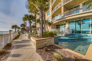 Un hotel sulla spiaggia con piscina, palme e una passeggiata.