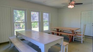 A room with a wooden table and benches, large windows, a ceiling fan, and a door. - It's Five O'clock Somewhere 6/3) (Panama City Beach)