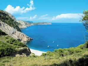 Eine Küstenlandschaft mit blauem Himmel, einem Sandstrand und felsigen Klippen.