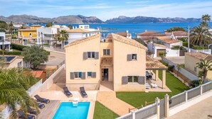 Une maison à deux étages avec une piscine, un jardin clôturé et une vue sur la mer.