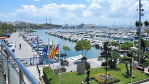Un port de plaisance où de nombreux bateaux sont amarrés, une promenade piétonne et un ciel dégagé.