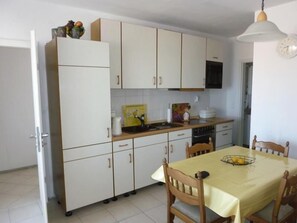 Compact kitchen with sink, stove, oven, and microwave, featuring a dining table and four chairs.