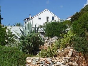 Set amidst lush gardens, this charming property features a stone wall and a pitched roof.