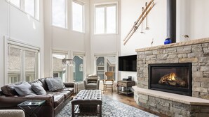 Amplia sala de estar con chimenea de piedra, sofá de cuero y un ventanal.
