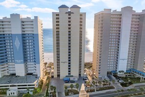 A high-rise hotel with multiple floors, a parking area, and a view of the beach. - Ocean Ritz by iTrip Panama City Beach (Panama City Beach)
