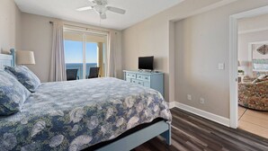 A bedroom with a bed, a ceiling fan, a dresser, and a TV. - Ocean Ritz by iTrip Panama City Beach (Panama City Beach)