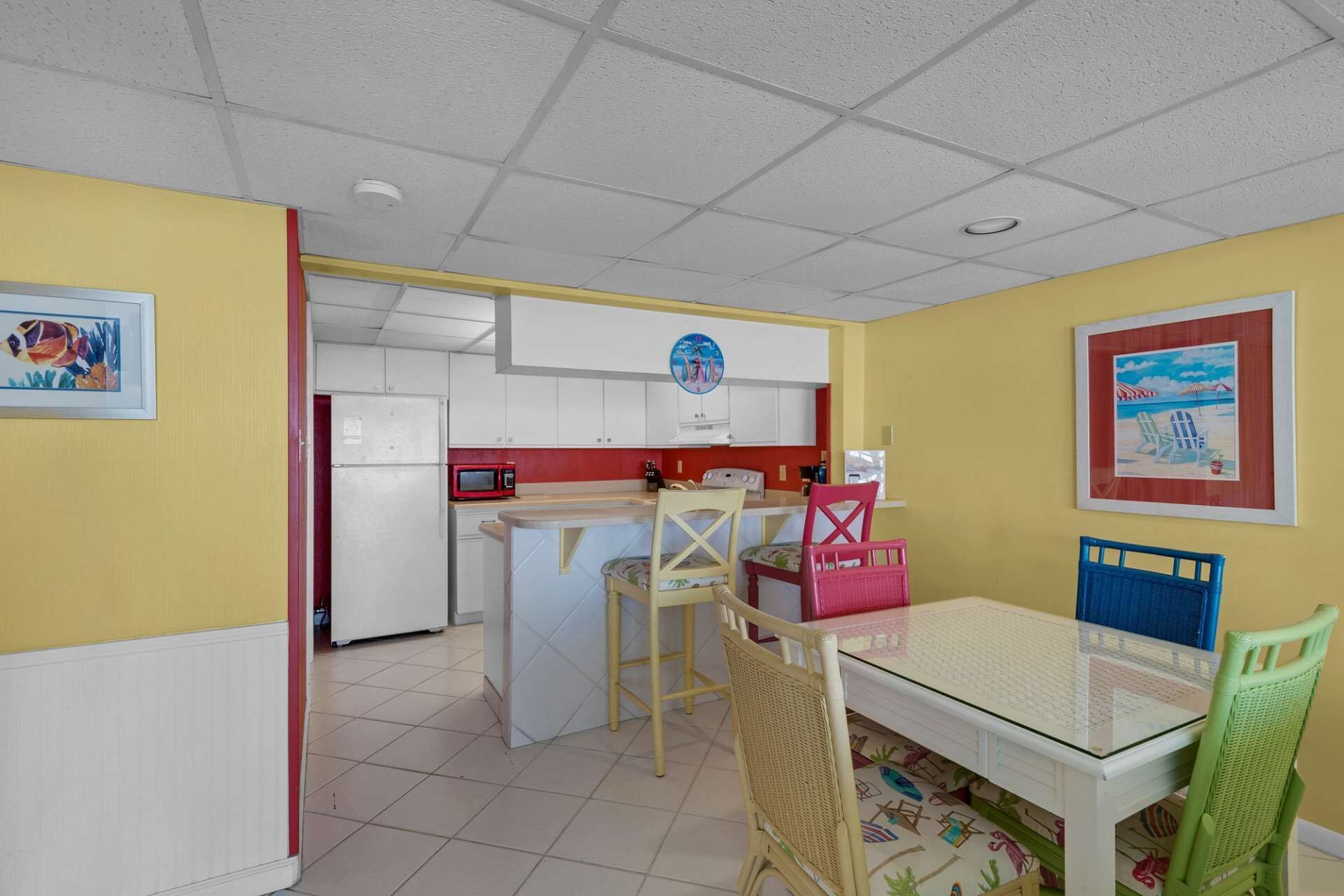 A compact kitchen with white cabinets, a red microwave, and a small island with stools.
