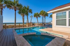 A pool area with a view of the ocean, surrounded by palm trees and a wooden deck. - Parrotdise on the Gulf (Panama City Beach)
