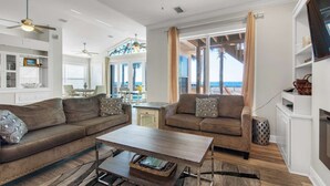 Un salon spacieux doté d’une grande fenêtre donnant sur la plage, et aménagé avec deux canapés et une table basse.