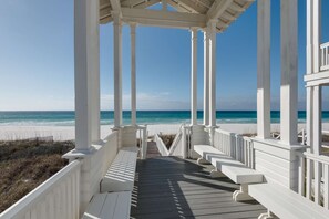 A wooden deck with white railings leading to a beach view. - Love Shack (Panama City Beach)