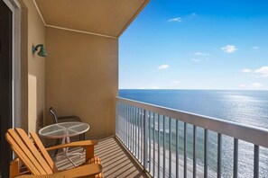 Varanda com mesa e cadeiras, com vista para uma praia e oceano.