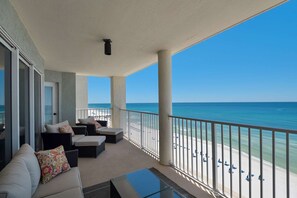Un balcon avec vue sur la plage, un canapé et une table en verre.
