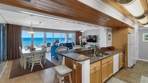 A modern kitchen with a large island, wooden cabinetry, and a view of the ocean. - Long Beach Resort by iTrip Panama City Beach (Panama City Beach)
