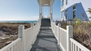 Un escalier en bois mène à un belvédère blanc d’où l’on a vue sur la plage.