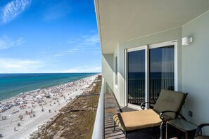 Uma varanda com vista para uma praia movimentada e o oceano.