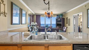 A kitchen with a granite countertop, stainless steel sink, and a Frigidaire dishwasher. - Marisol by iTrip Panama City Beach (Panama City Beach)