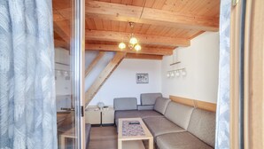 Une pièce chaleureuse avec un plafond en bois, un canapé, une petite table et un luminaire suspendu au plafond.