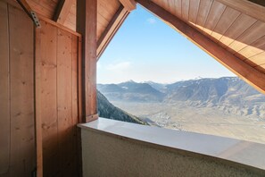 Een kamer met een houten plafond en uitzicht op een bergachtig landschap.