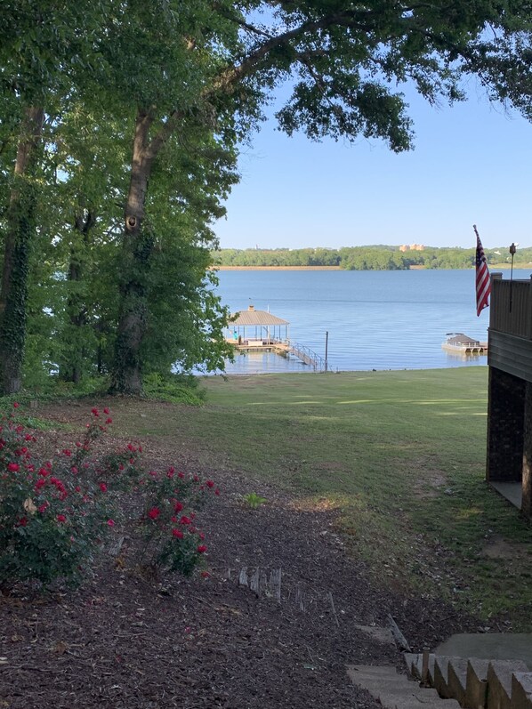 A lakeside view with a dock, an American flag, and a gazebo.