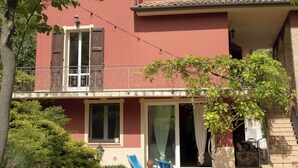 Un bâtiment à deux étages doté d’un balcon, d’un espace piscine avec des chaises longues et d’un jardin.