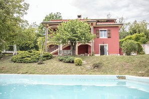 Ein zweistöckiges Haus mit einem Schwimmbecken im Vordergrund.