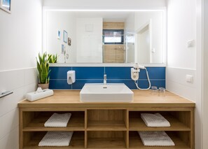 A modern bathroom with a large mirror, white sink, and wooden vanity.